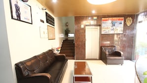 Un vestíbulo con un sofá de cuero marrón, una mesa de centro de madera, un sillón de cuero marrón y un mostrador de recepción.