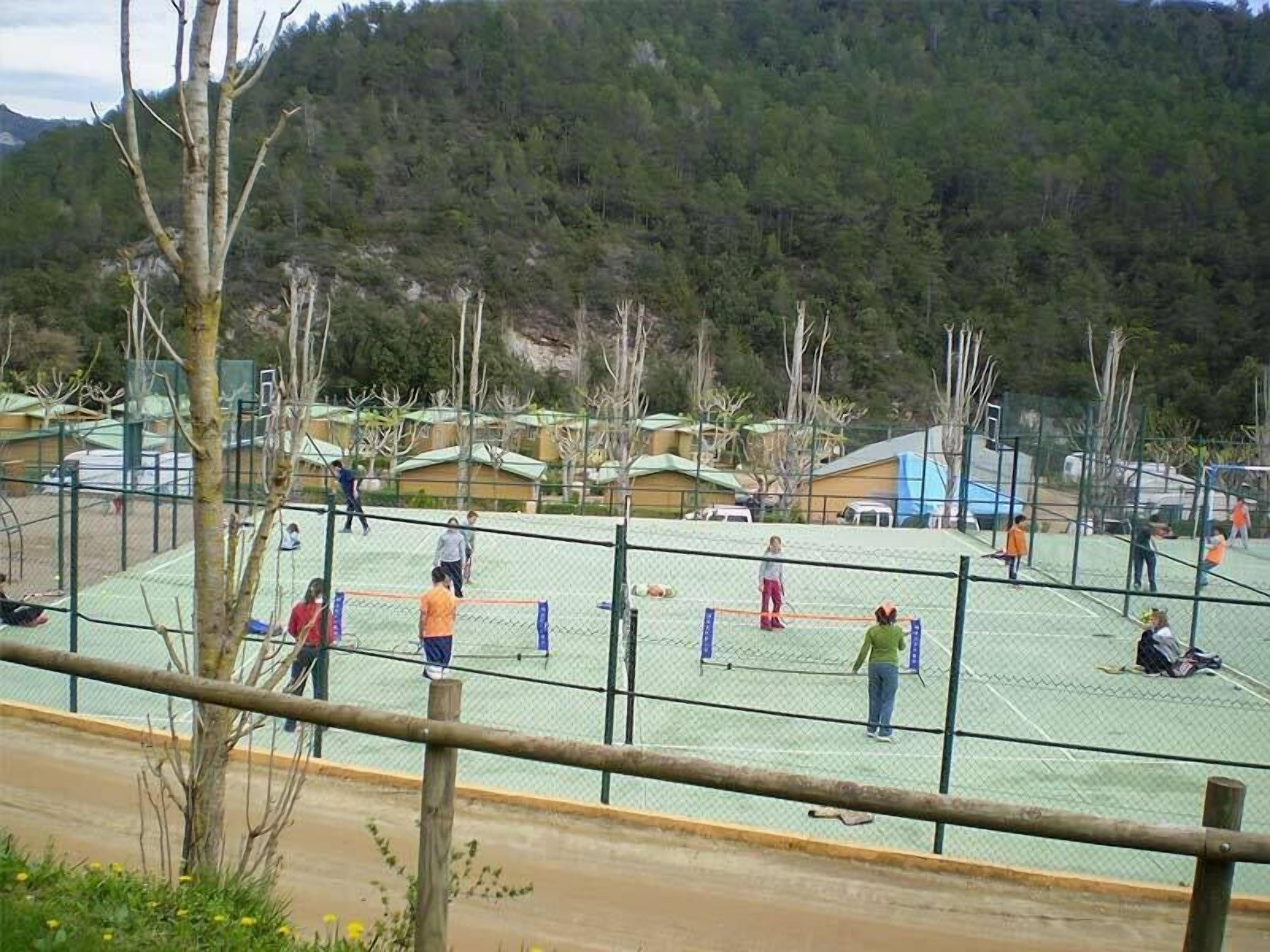 Una cancha deportiva con una red, rodeada de árboles y edificios.