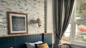 A hotel room with two beds, a framed picture on the wall, a lamp, and a view of the outside through a window. - Anchor Inn by Greene King Inns (Seaton)