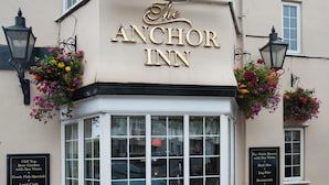 The Anchor Inn with a signboard, flower baskets, and a window displaying the menu. - Anchor Inn by Greene King Inns (Seaton)