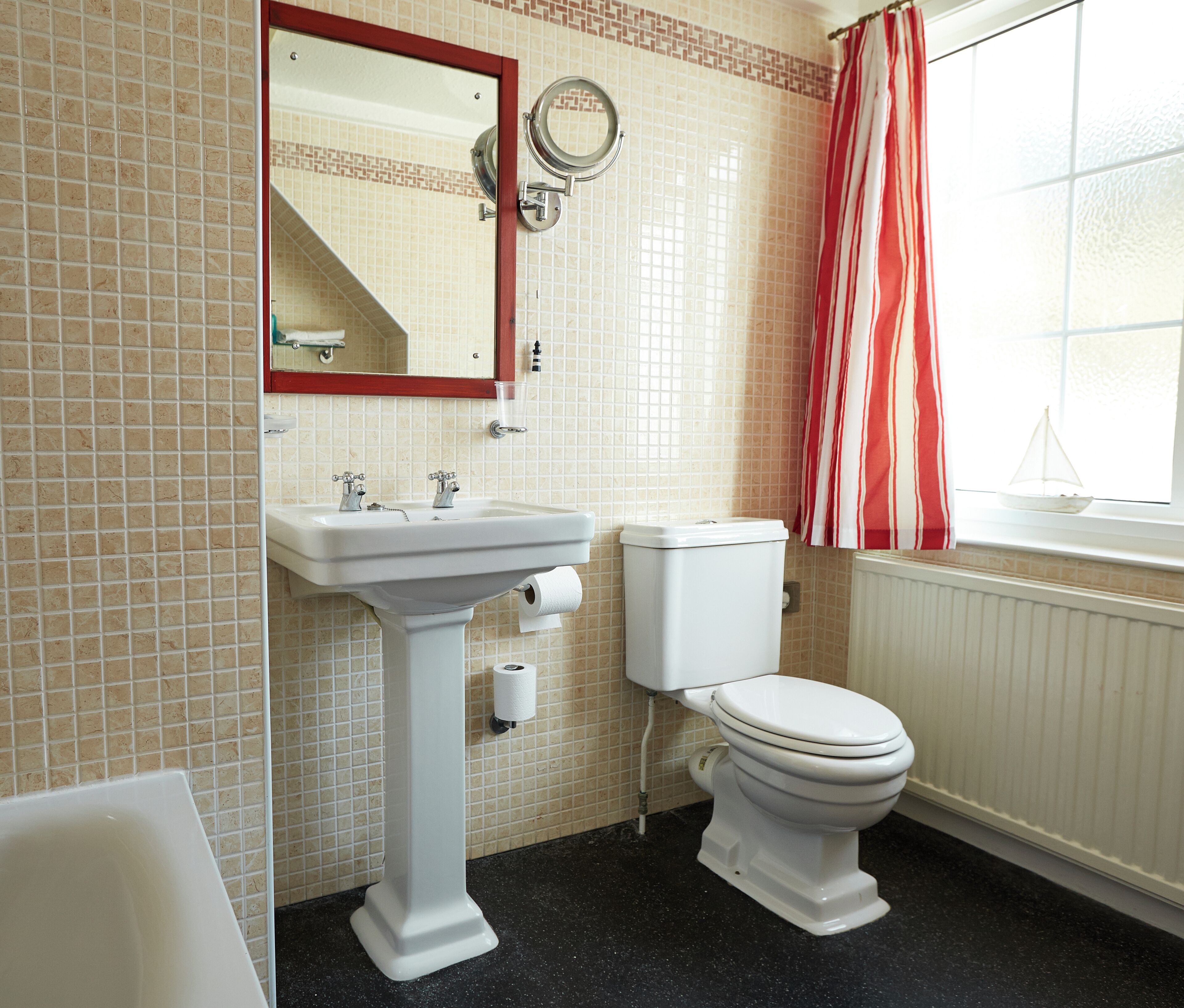 A bathroom with a white sink, toilet, and a mirror above the sink.