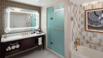 A bathroom with a vanity, a mirror with lights, a shower, and a bathtub.