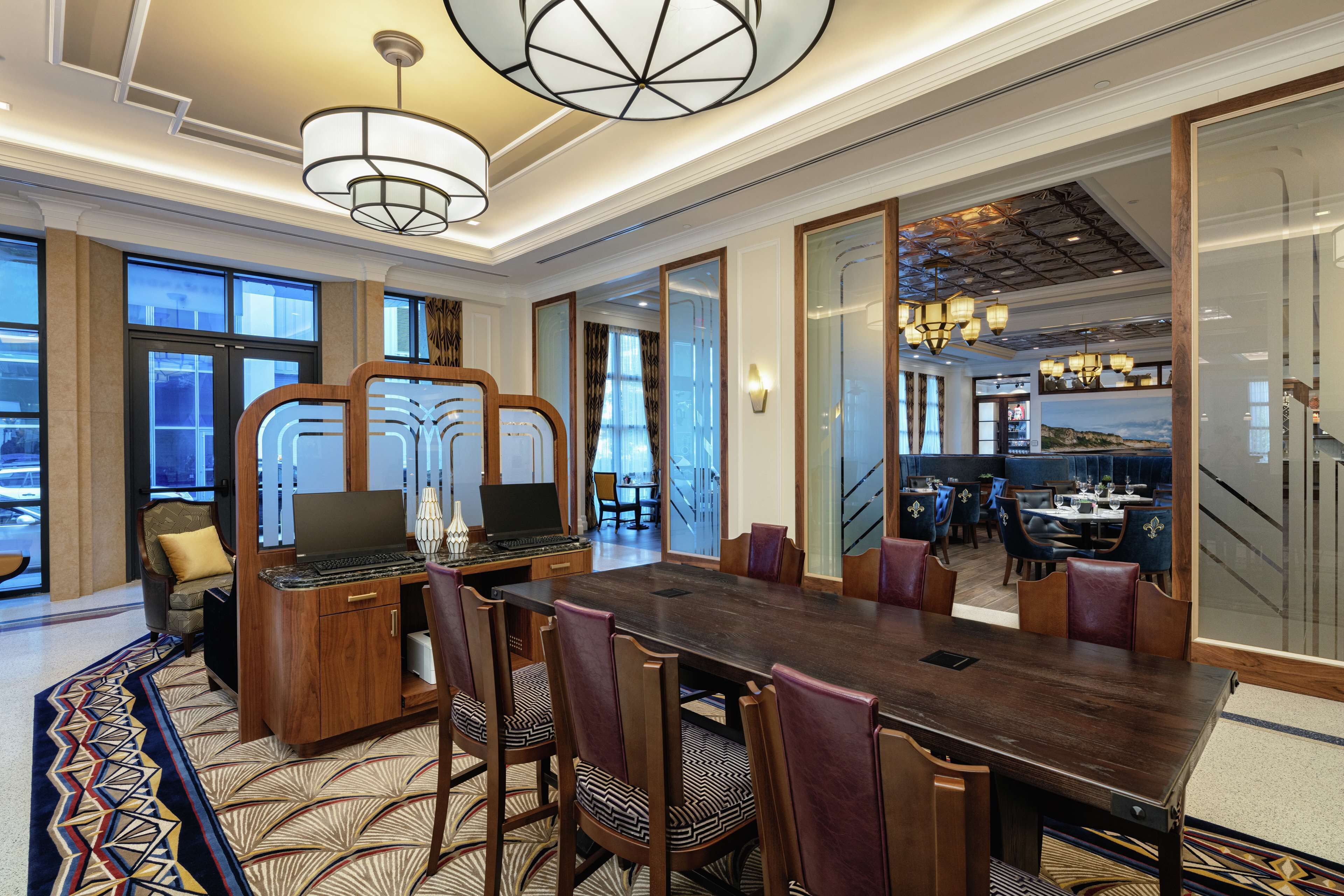 A spacious conference room with a large wooden table, comfortable chairs, and a laptop on a wooden desk.