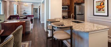 A modern kitchen with granite countertops, stainless steel appliances, and a bar area.
