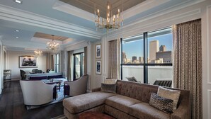 A spacious living room with a large sectional sofa, a dining area, and a city view through large windows.
