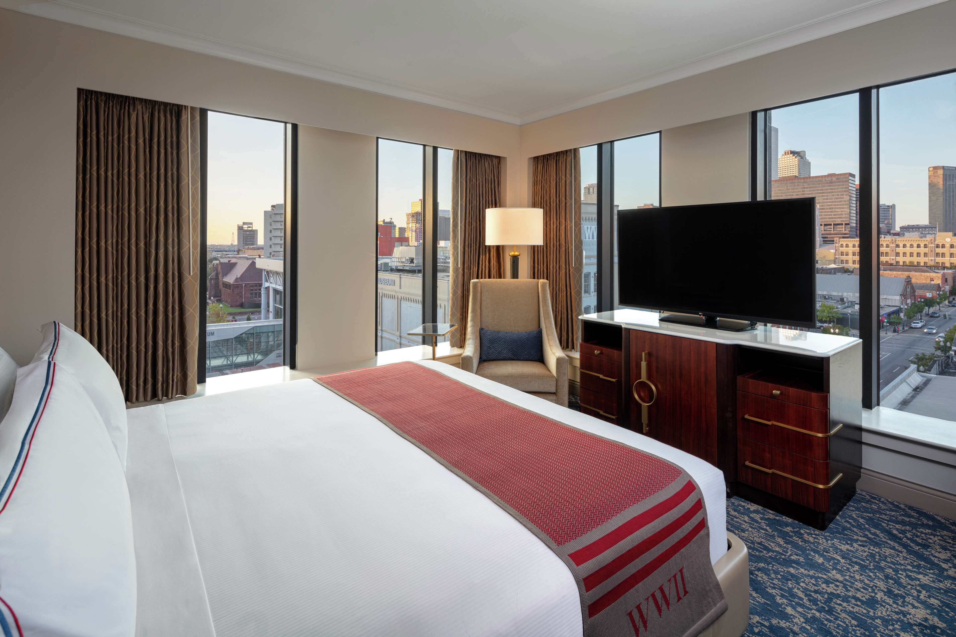 Habitación de hotel con una cama grande, televisión, escritorio y vistas a la ciudad.