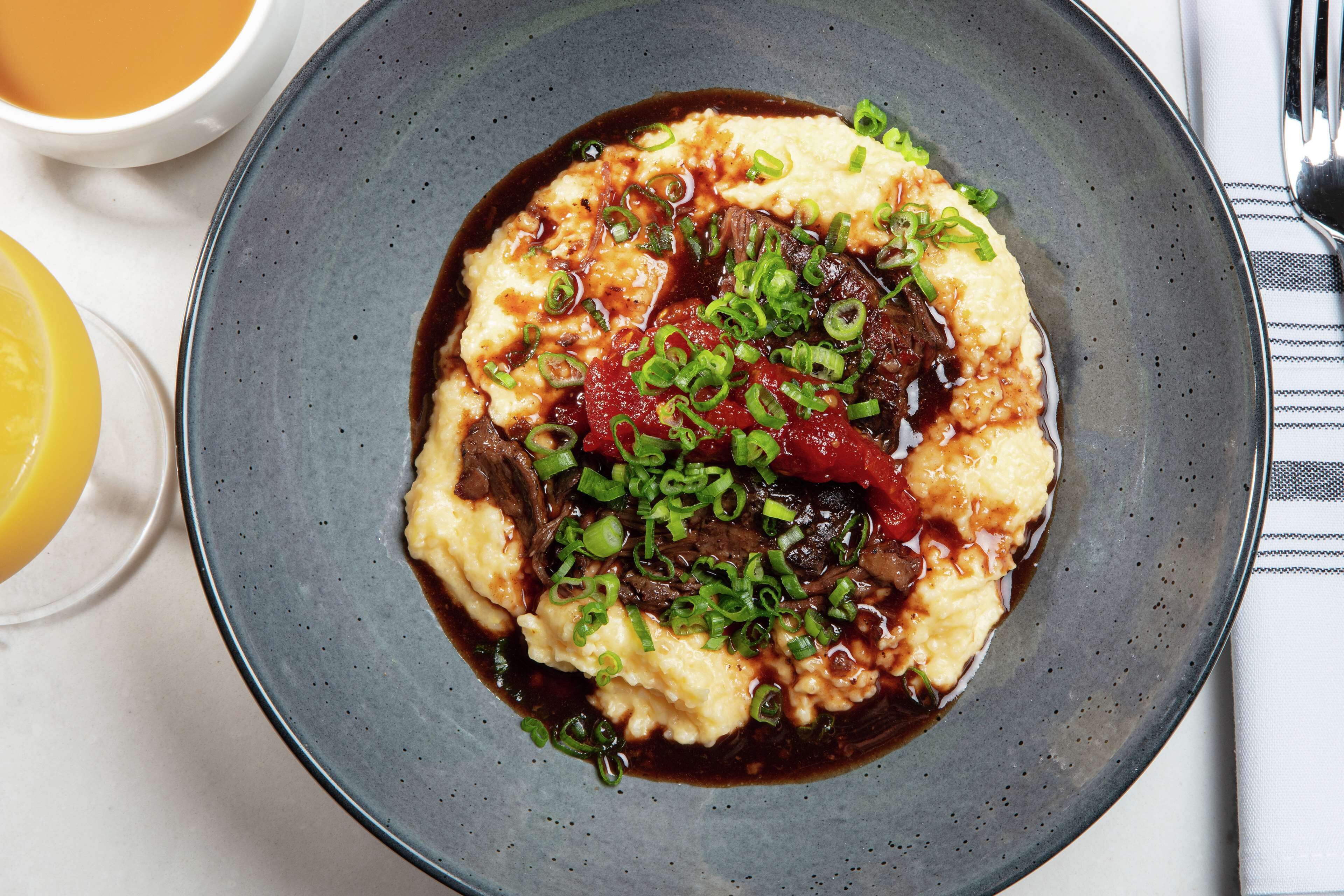 A plate of food with a dark sauce, green onions, and a lemon wedge.