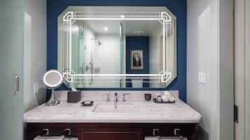 A bathroom with a large mirror, two sinks, a towel rack, and a framed picture on the wall.