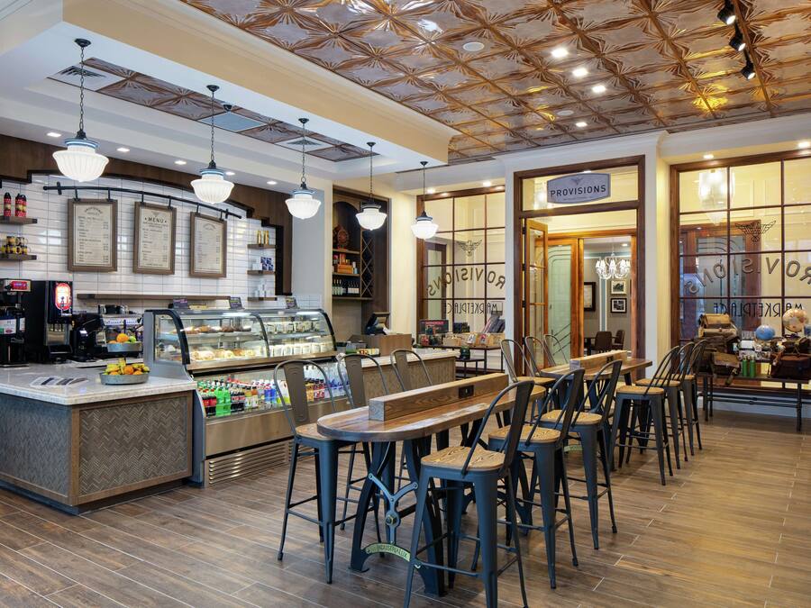 A café with a central counter, seating area, and a visible menu board.
