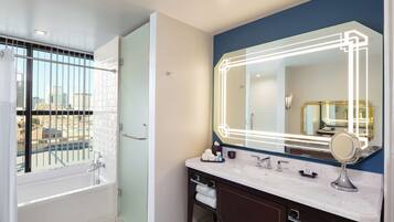 Un baño moderno con un espejo grande, una bañera y un tocador con encimera de mármol.