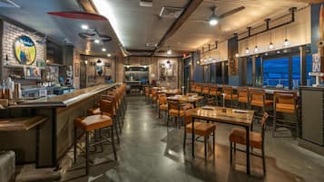 A restaurant with a bar area, wooden tables, and chairs.