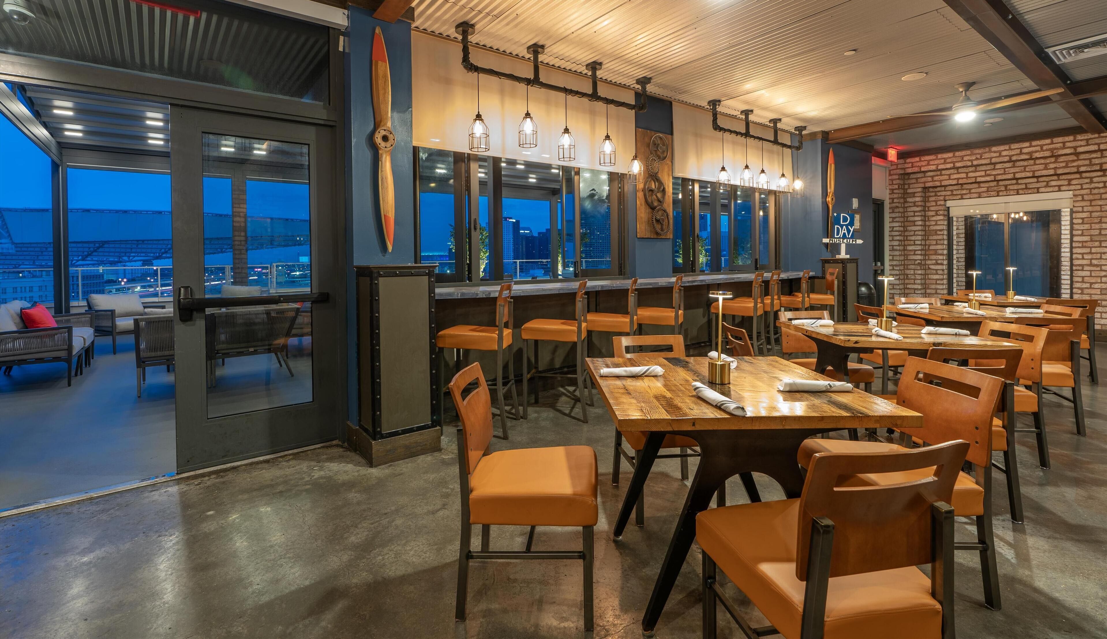 A restaurant with a modern interior, large windows, and a view of the cityscape.