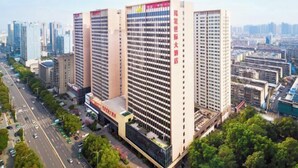 Un edificio de gran altura con varios pisos, rodeado de otros edificios y una calle concurrida.