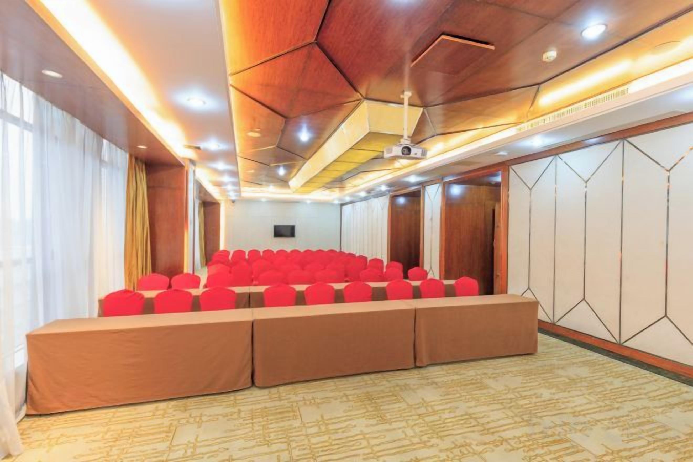 A conference room with a long table and chairs, a projector screen, and a wooden ceiling.