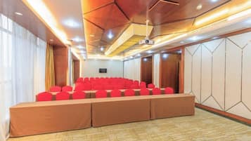 A conference room with a long table and chairs, a projector screen, and a wooden ceiling.