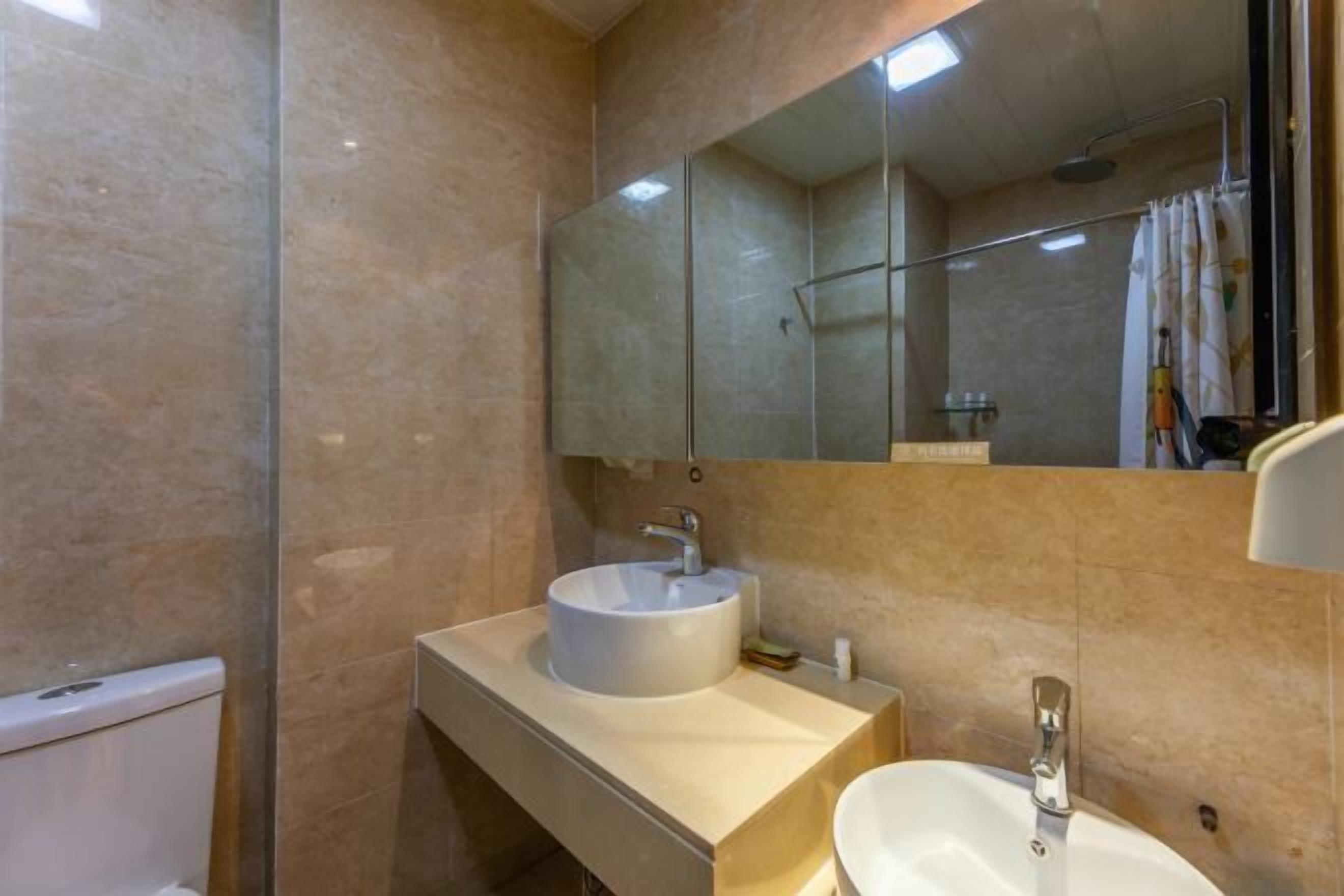 Un baño con un lavamanos blanco, un espejo y zona de ducha.