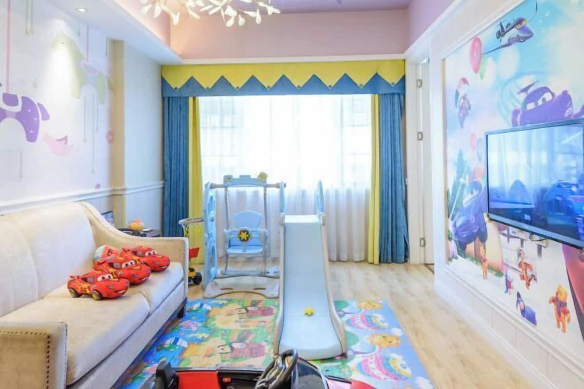 Una sala de juegos infantil con sofá, colchoneta, tobogán y televisor.