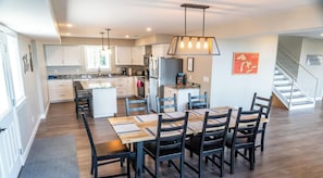A modern kitchen with white cabinets, a central island, and a dining area with a wooden table and chairs.