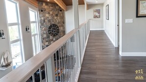 A spacious hallway with a wooden ceiling, stone wall, and a clock.