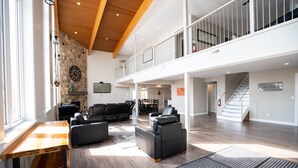 A spacious living area with a high ceiling, a stone wall, and a staircase leading to an upper level.