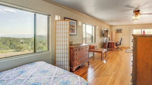 A bedroom with a large bed, wooden dresser, desk, and chair, a view of the outdoors, and a ceiling fan. - Sunroom + Sauna! Mtn-View Prescott Valley Home (Prescott Valley)