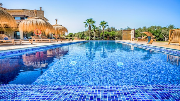 A swimming pool with blue mosaic tiles, sun loungers, and palm trees. - Great Villa with pool, playground, 5km to the beach Es Trenc, Campos, Mallorca (Campos)