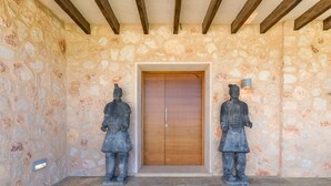 A stone wall with a wooden door and two statues. - Great Villa with pool, playground, 5km to the beach Es Trenc, Campos, Mallorca (Campos)