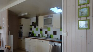 Cozinha com armários brancos, máquina de lavar louça e micro-ondas. Há uma janela com vista para um prédio.
