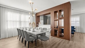 A modern dining room with a large table, chairs, and a chandelier.