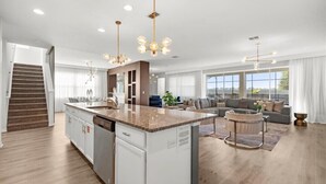 A spacious living area with a large island, a staircase, and a modern kitchen.