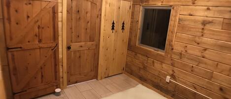 Una habitación de madera con dos puertas, una ventana y una cama.