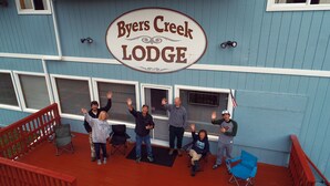 A group of people standing on a porch with a sign that reads "Byers Creek Lodge". - Byers Creek Lodge Eagle Cabin in Denali State Park Trapper Creek Alaska (Trapper Creek)