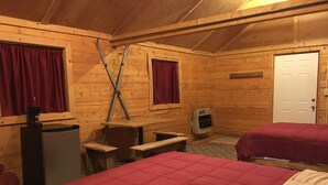A wooden cabin room with two beds, a desk, a chair, a refrigerator, and a heater. - Byers Creek Lodge Eagle Cabin in Denali State Park Trapper Creek Alaska (Trapper Creek)