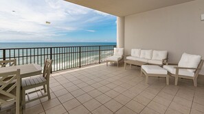 A balcony with a view of the sea, featuring a table, chairs, and a sofa.