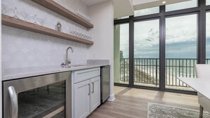 A modern kitchen with a large window overlooking a beach. - The Oasis of Orange Beach  1011 (Orange Beach)