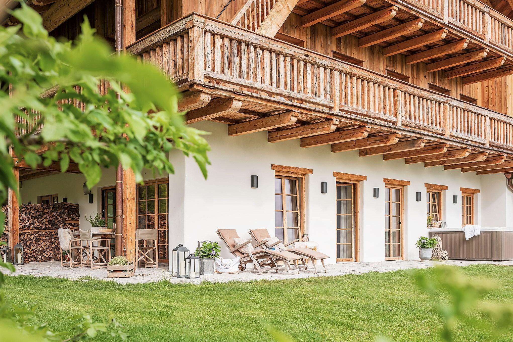 A wooden chalet with a balcony, outdoor seating, and a well-maintained lawn.