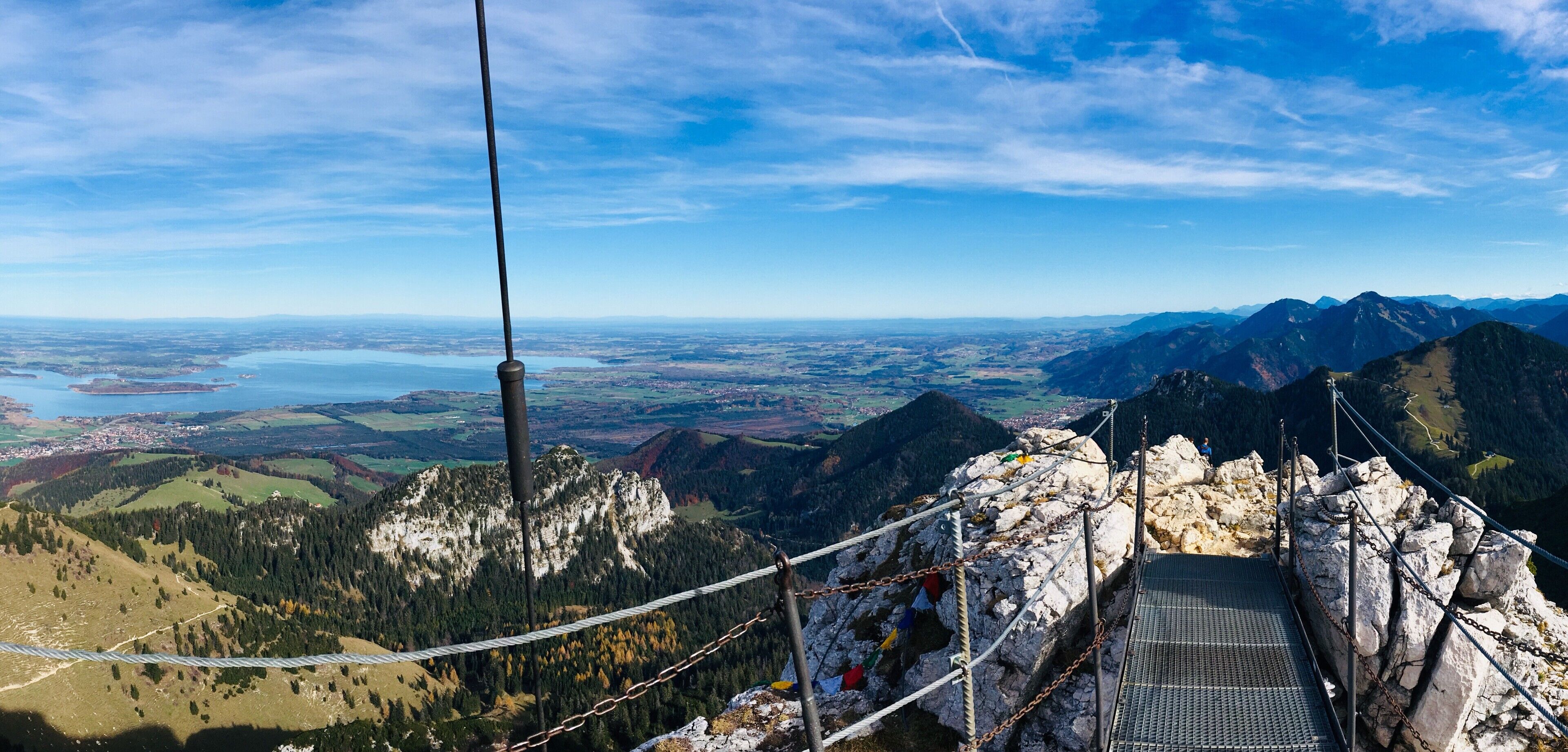 A mountain view with a suspension bridge, rocky terrain, and a distant lake.