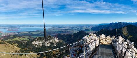 A mountain view with a suspension bridge, rocky terrain, and a distant lake.