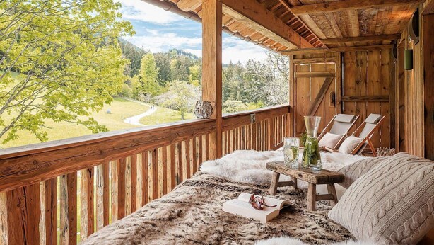 A wooden deck with a view of a forest and a winding road. - Chiemsee Chalet (Frasdorf)