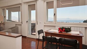 A balcony with a table and chairs, a view of the sea, and a cityscape in the distance. - Villa Solelago Exclusive (Lonato del Garda)