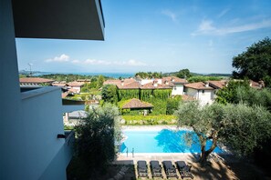 Une vue sur une piscine entourée d’une végétation luxuriante et de bâtiments traditionnels.
