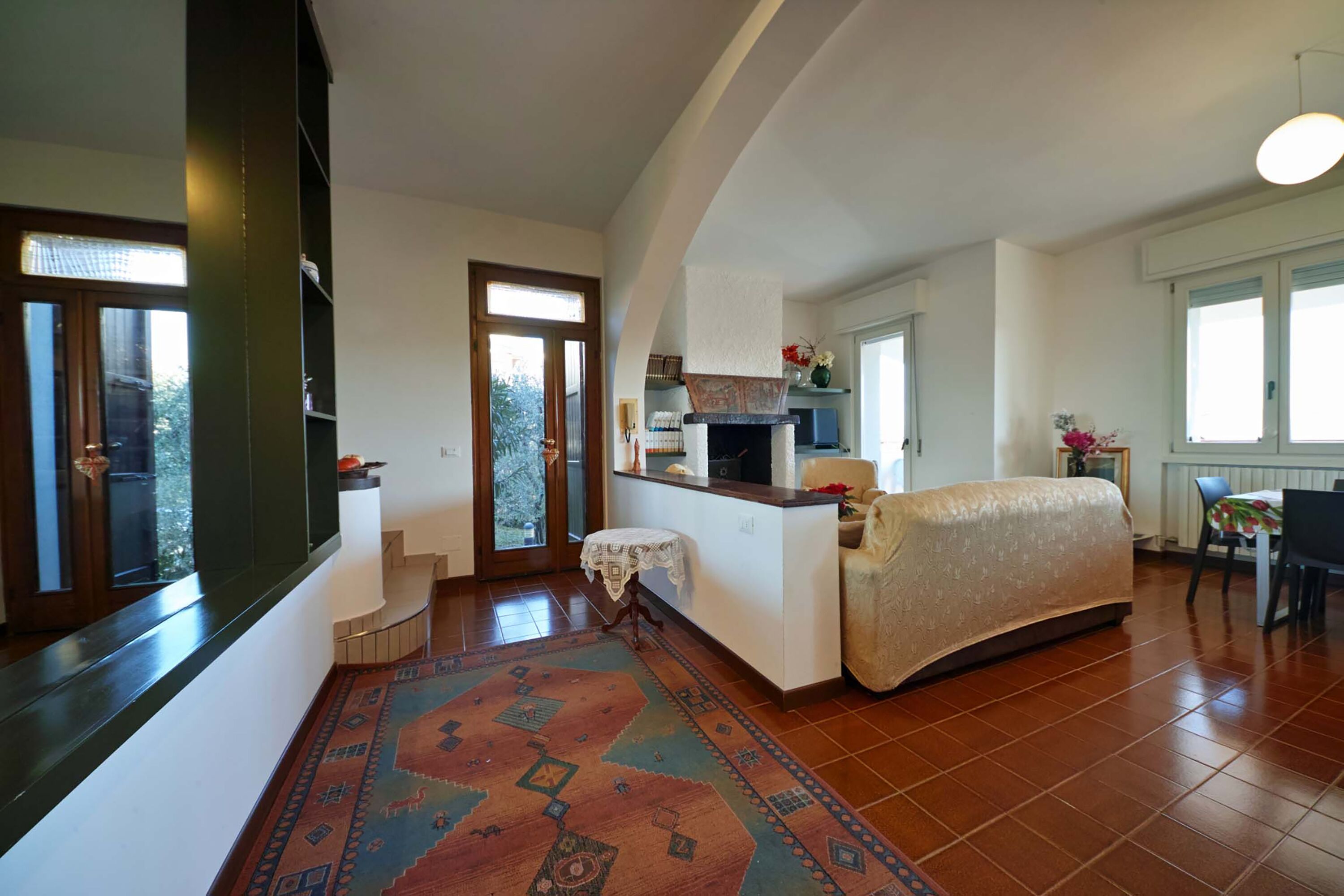 A spacious living room with a sofa, a patterned rug, and a kitchen area with a stove and sink.