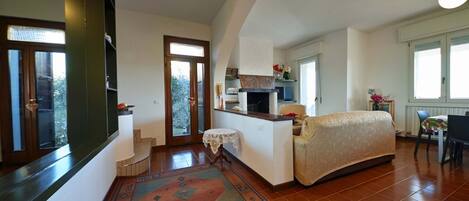 A spacious living room with a sofa, a patterned rug, and a kitchen area with a stove and sink.