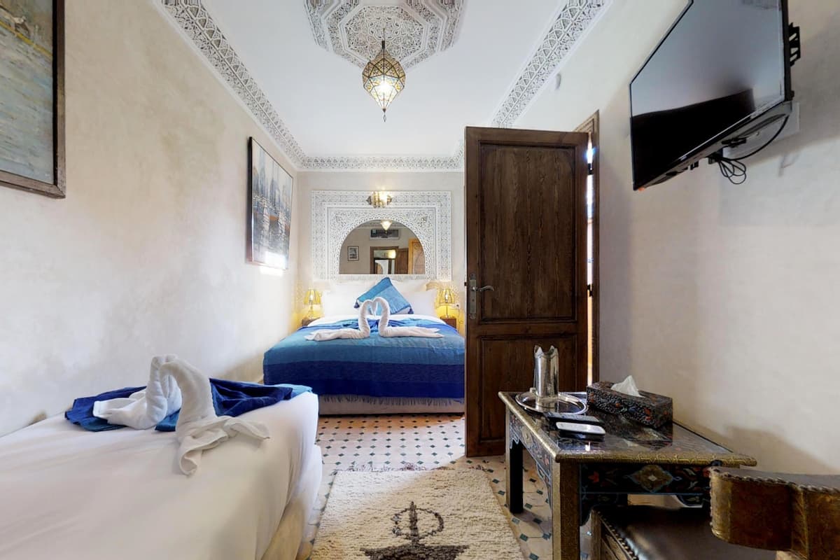 A hotel room with a bed, a desk, a television, and a decorative ceiling.