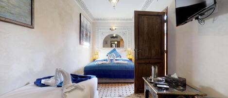 A hotel room with a bed, a desk, a television, and a decorative ceiling.
