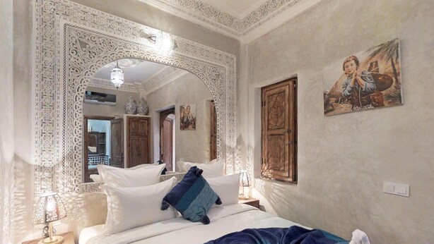 Una camera da letto con un letto grande, uno specchio decorativo e un quadro appeso al muro.