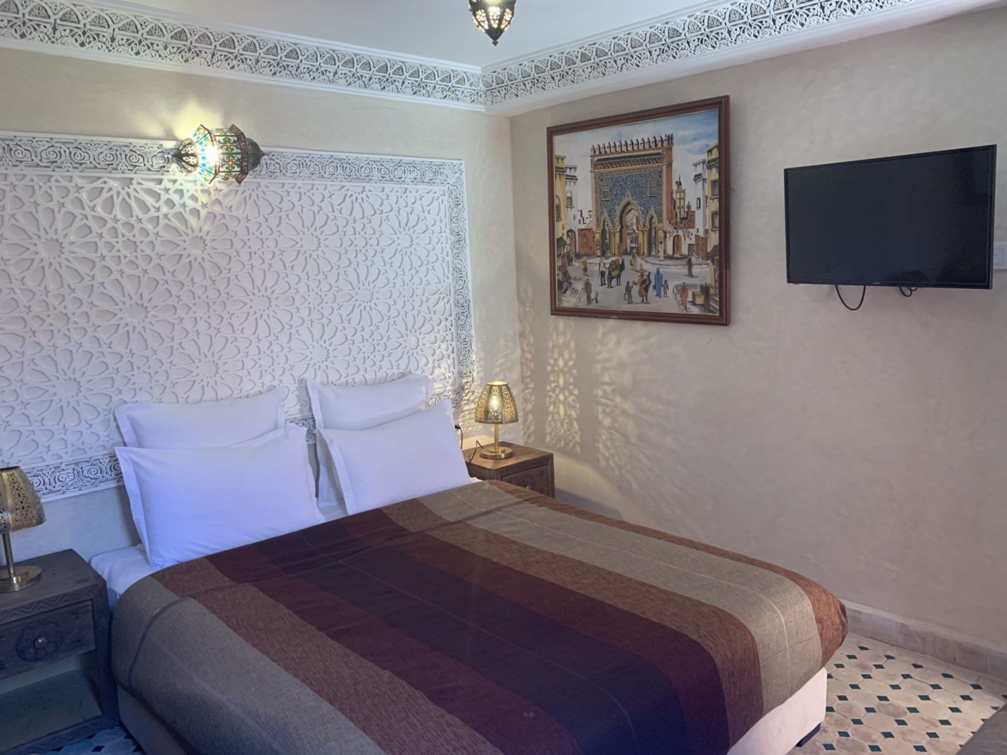 Ein Hotelzimmer mit einem großen Bett, einem wandmontierten Fernseher und einem dekorativen Gemälde.