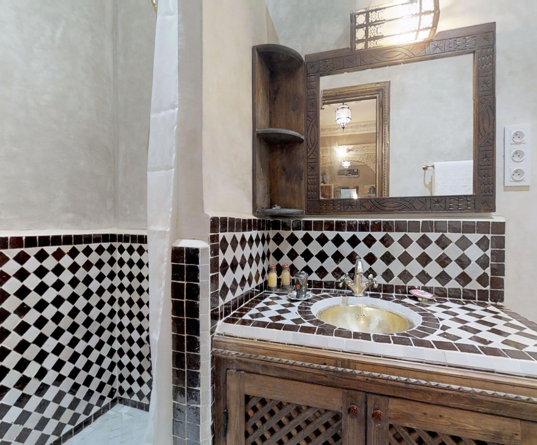 A bathroom with a checkered tile pattern, a sink with a wooden cabinet, and a mirror with a decorative frame.