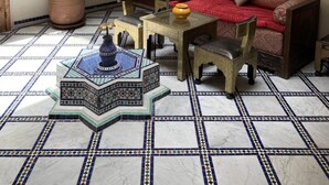 Un interno tradizionale con pavimento piastrellato, un divano, un tavolo e una grande pianta in vaso.