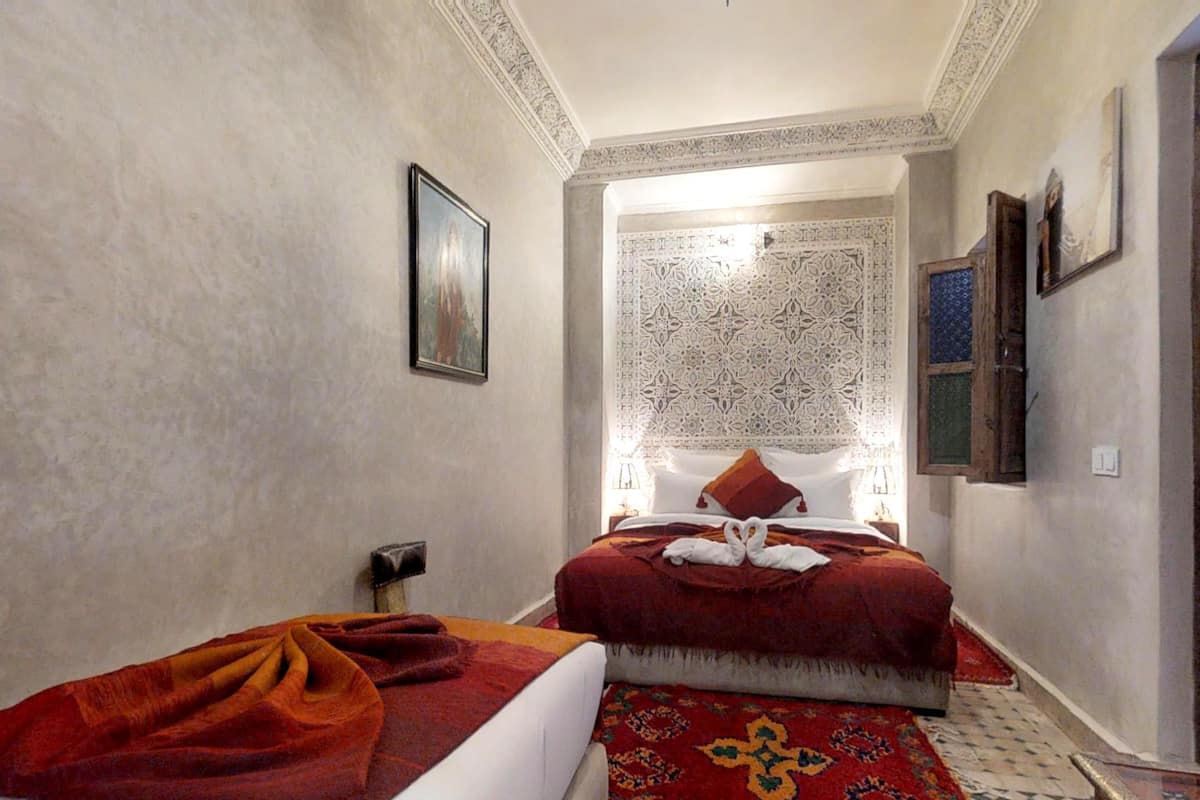 A hotel room with two beds, a patterned wall, and a decorative ceiling.